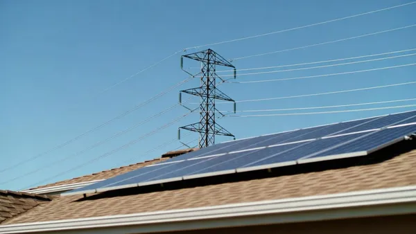 Linhas de distribuição de energia sobre telhados residenciais com painéis solares em dia de sol