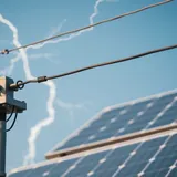 Dispositivo de proteção contra surtos instalado em quadro elétrico de sistema solar off-grid isolado com painel e baterias ao fundo
