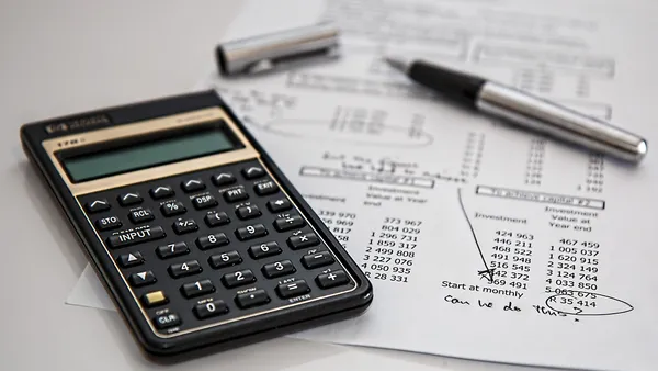 Calculadora financeira e planilha de financiamento sobre mesa com gráficos de TIR e VPL