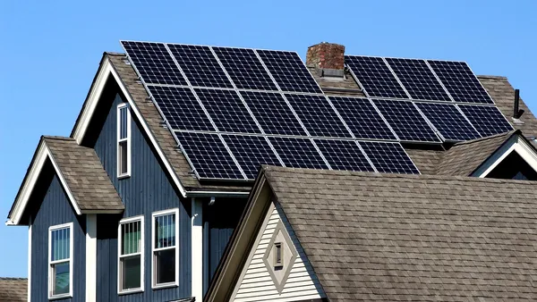 Família observa medidor bidirecional ao lado de telhado com painéis solares fotovoltaicos